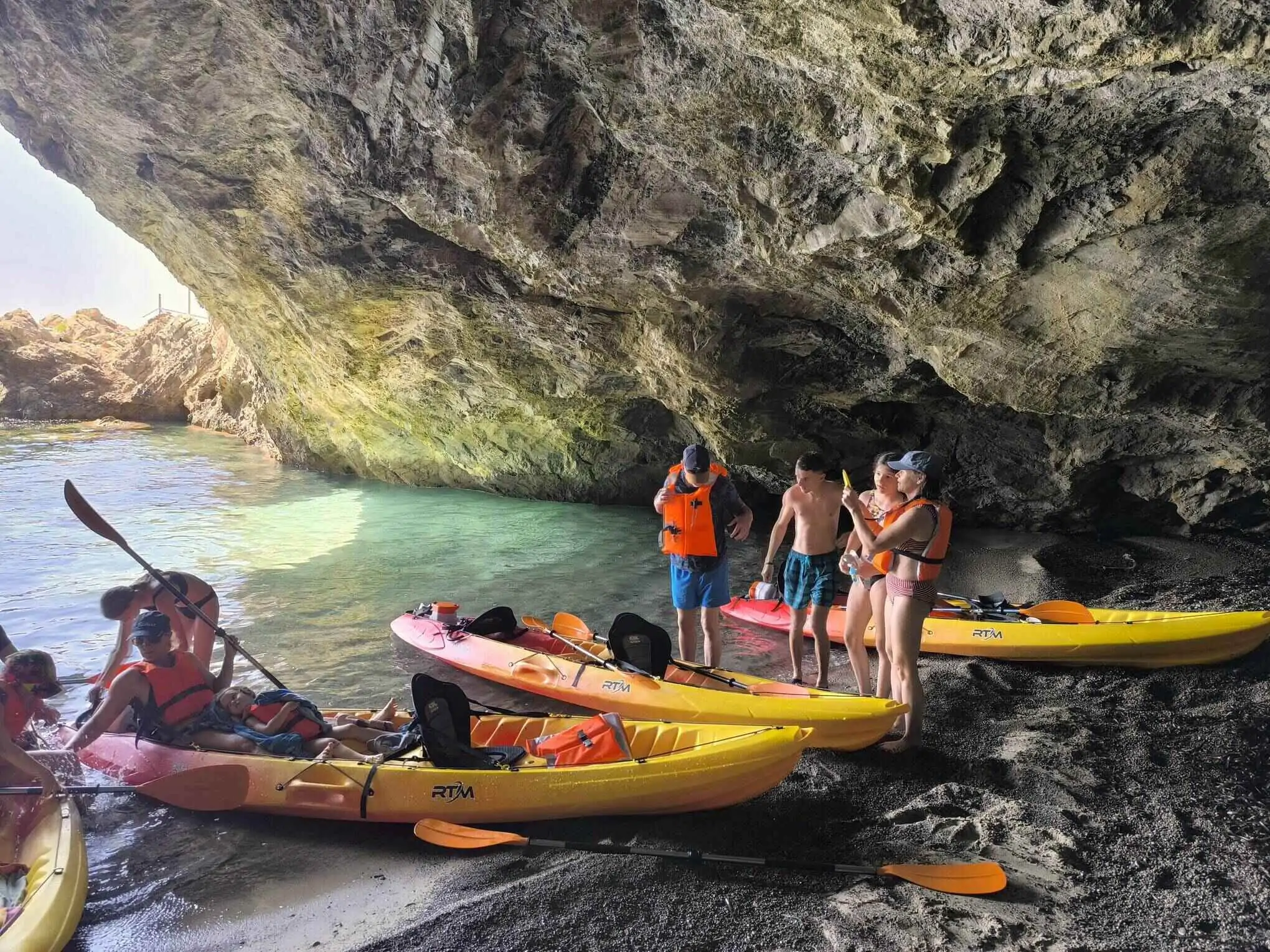A sandy beach inside a cave offers shade during a kayak trip with family