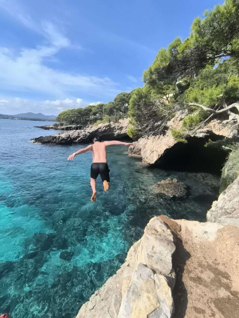 A man jumps from a rock into the sea